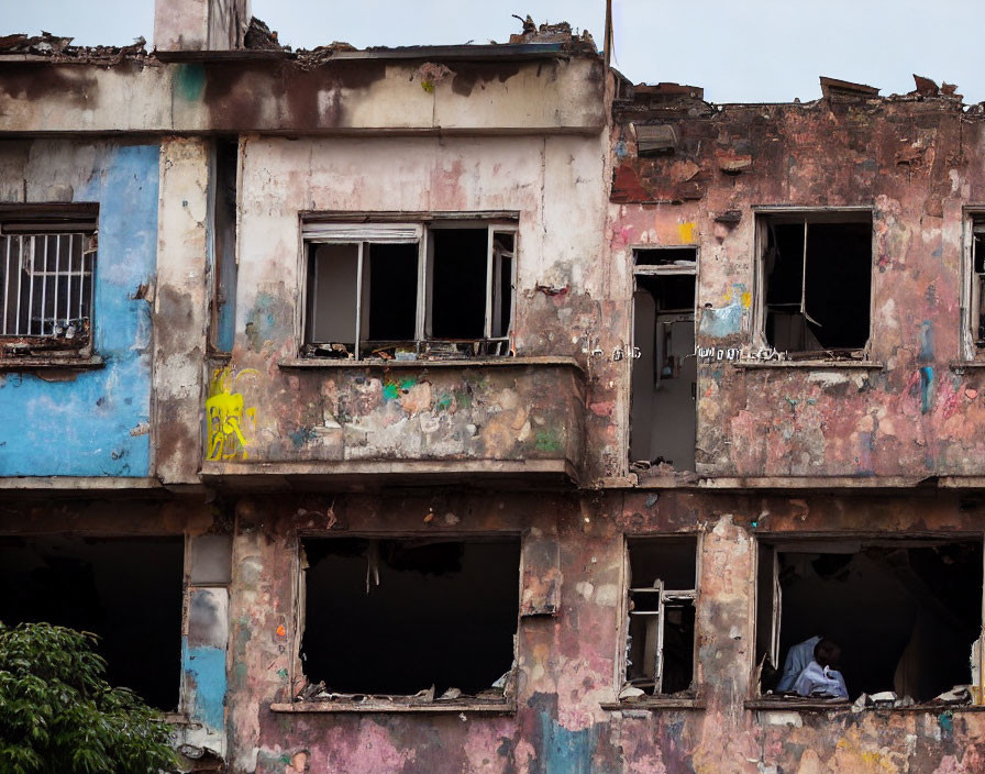 Decrepit multi-story building with peeling paint and broken windows.