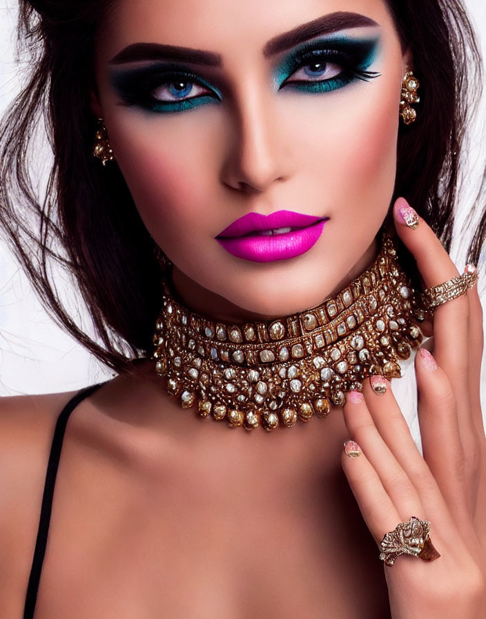 Woman with bold eye makeup and pink lipstick in gold choker and rings