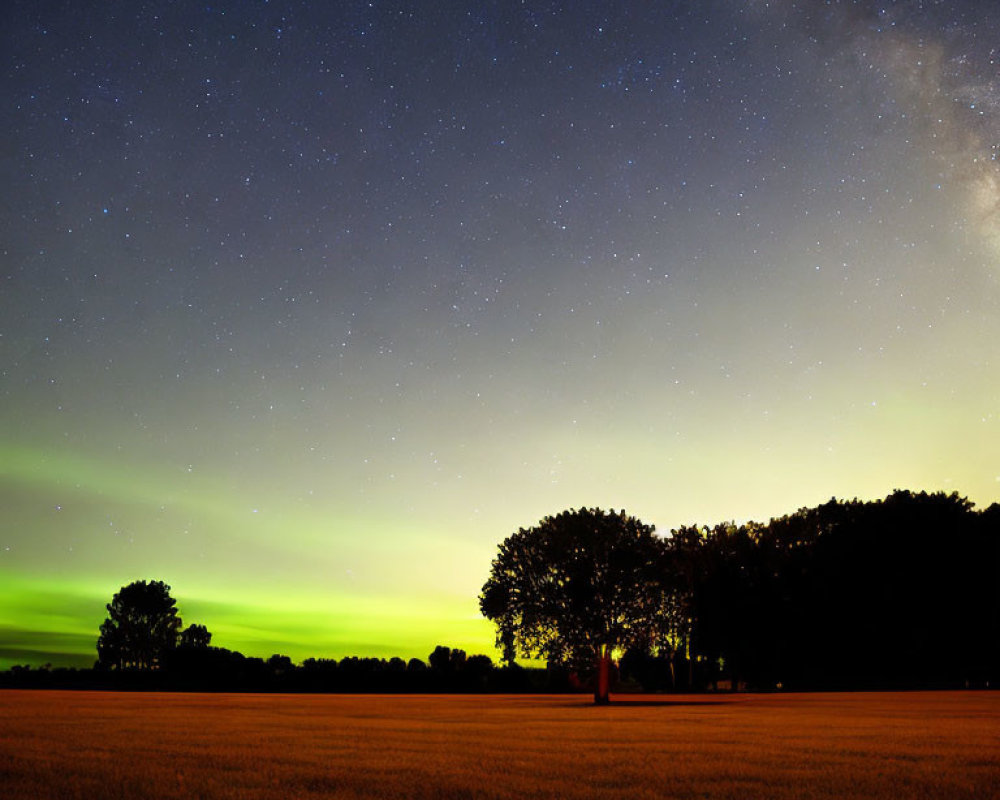 Serene field under starry night sky and Milky Way with sunset glow