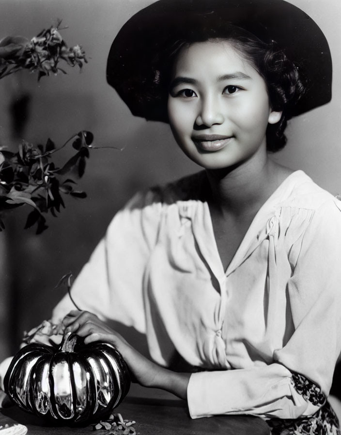 Vintage Black and White Photo of Smiling Woman with Wide-Brimmed Hat and Pumpkin