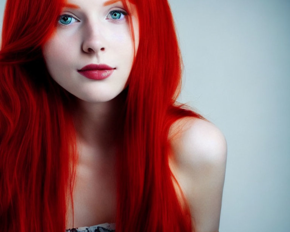 Red-haired woman with blue eyes and porcelain skin in subtle makeup gazes at camera