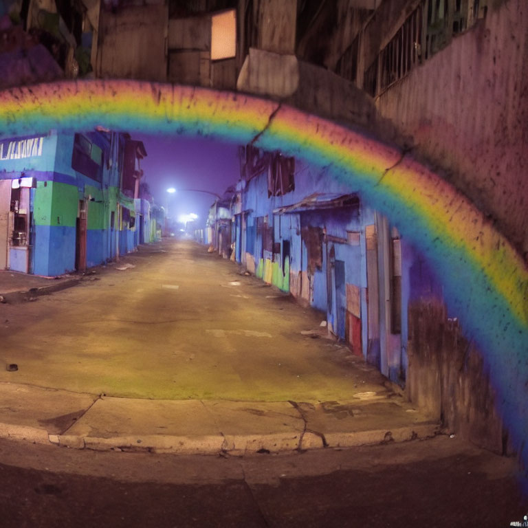 Colorful rainbow mural in urban night scene with deserted street and buildings.