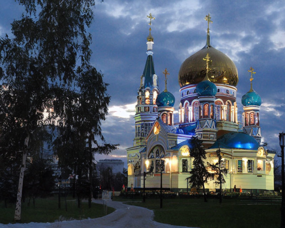 Orthodox cathedral with golden domes in evening light, set in lush scenery.