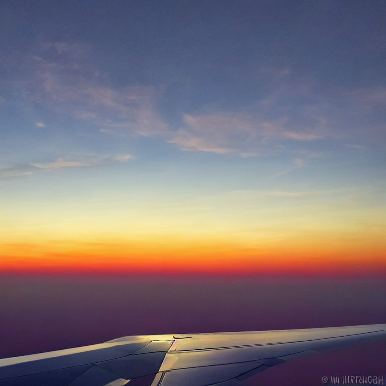 Vibrant sunset aerial view above clouds with airplane wing