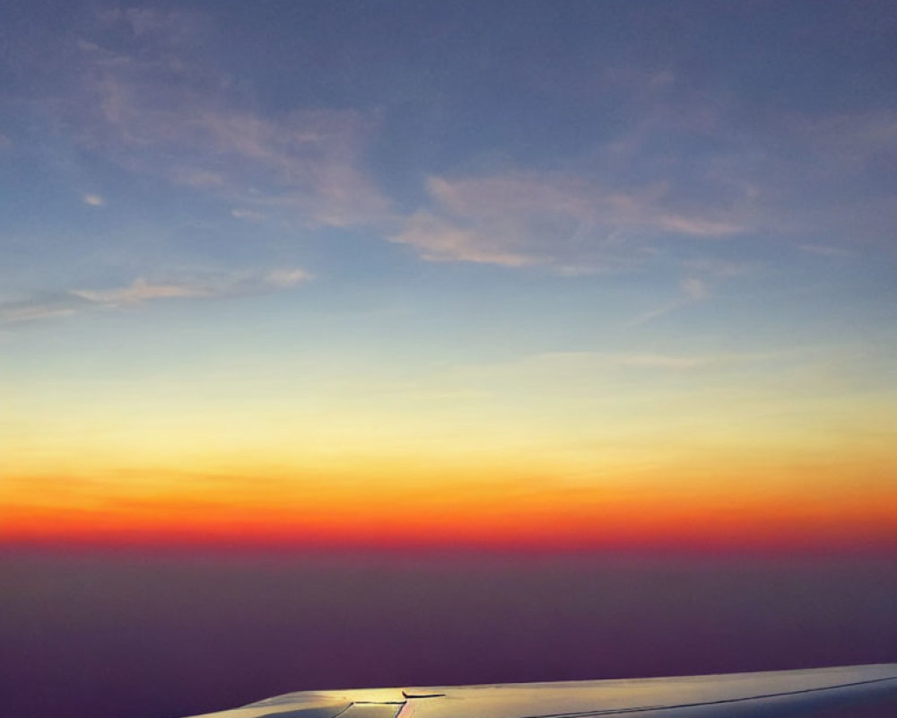 Vibrant sunset aerial view above clouds with airplane wing