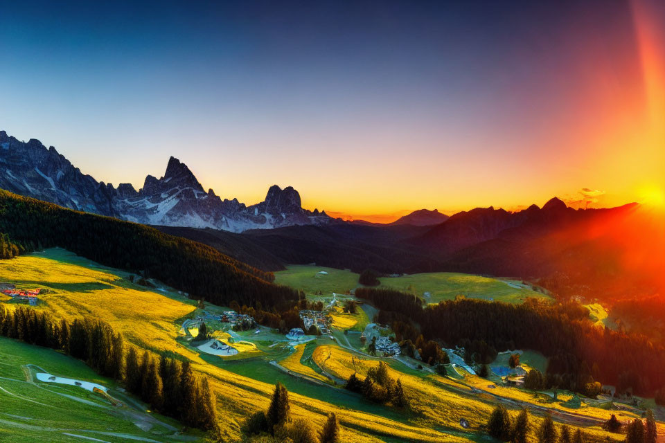 Vibrant sunset colors over mountain valley with scattered buildings