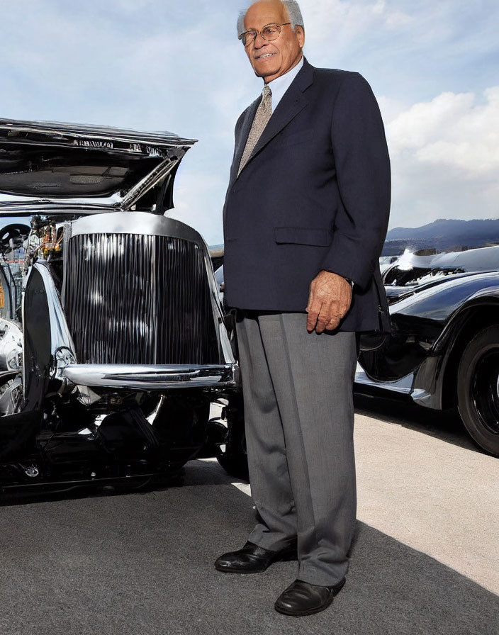 Elegant individual next to open classic car hood under clear sky