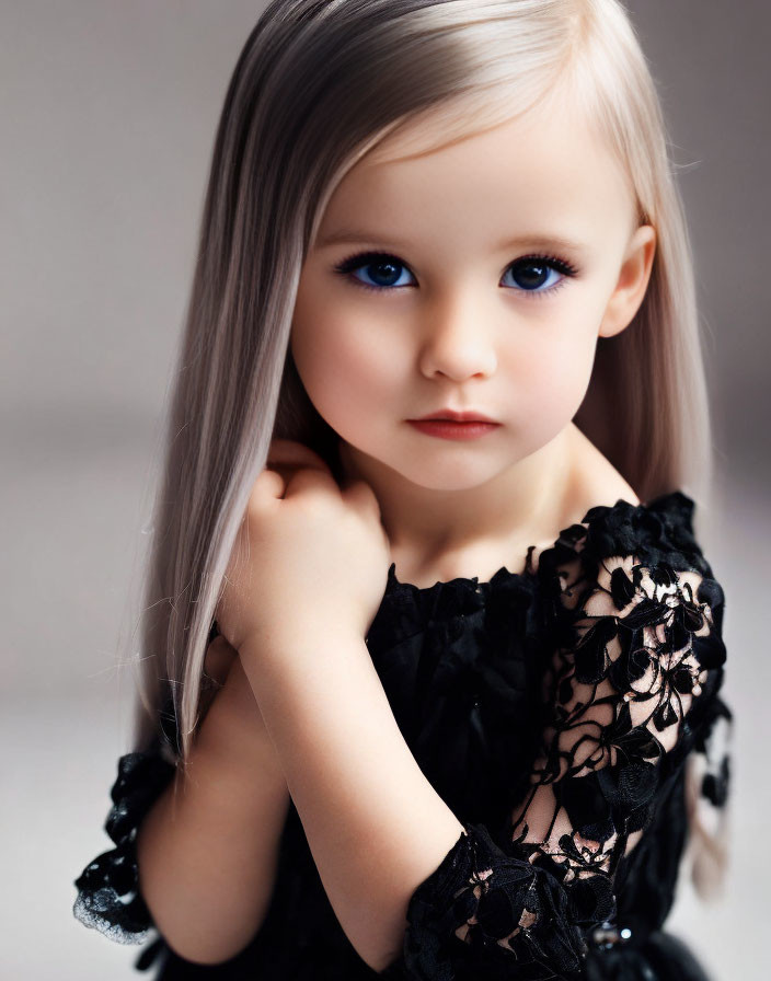 Young girl with blue eyes and blonde hair in black lace dress.