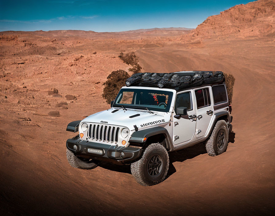 White off-road vehicle navigating rocky desert terrain under clear blue sky