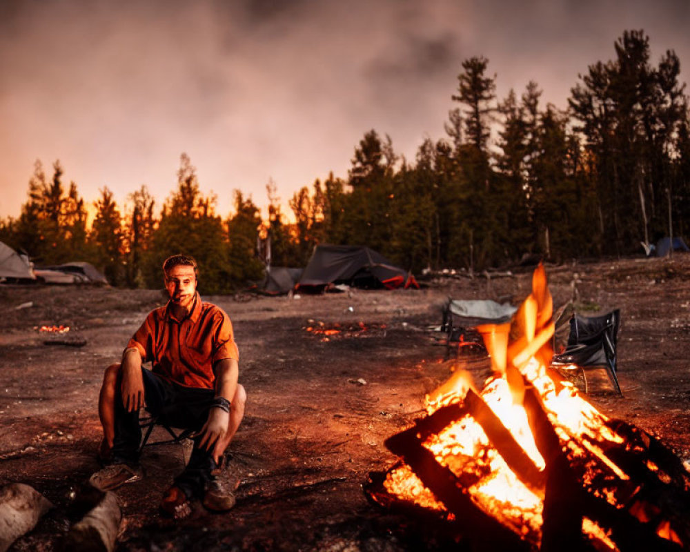 Person sitting by bonfire at dusk in wooded camping area