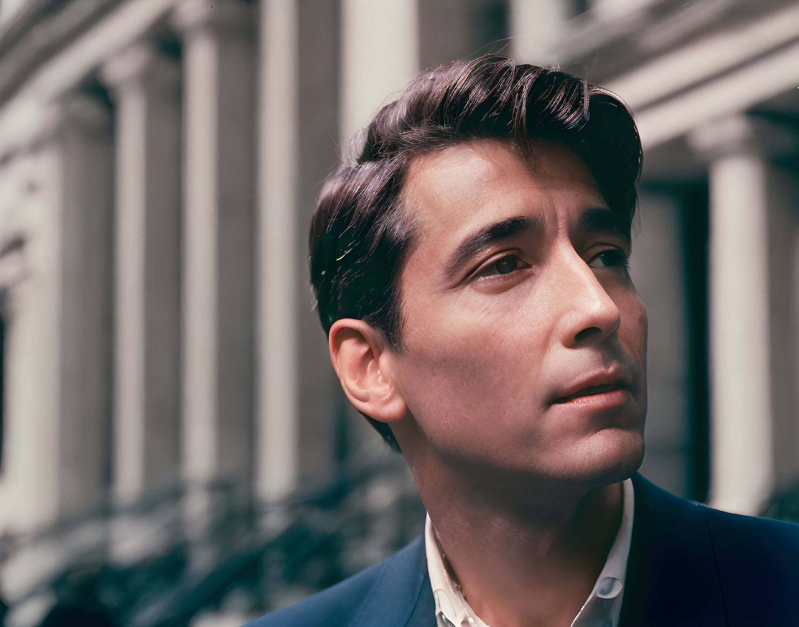 Man with Swept-Back Hair Contemplating Against Classical Columns