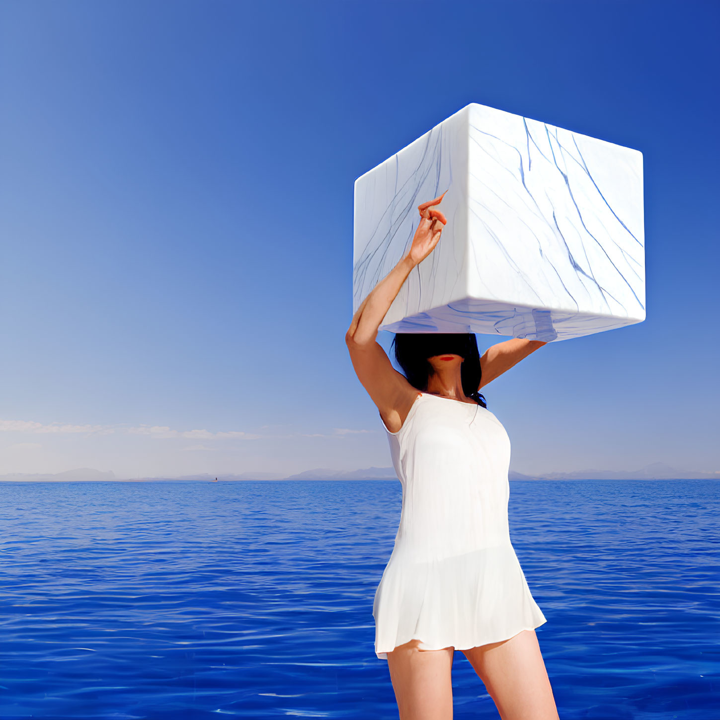 Person balancing large white cube with blue marble patterns by calm sea