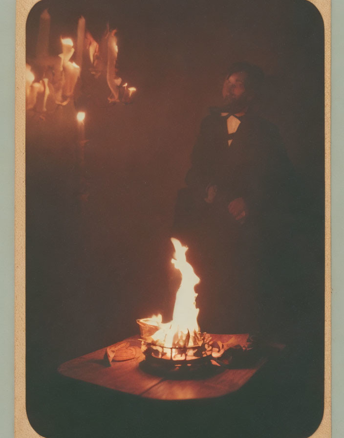 Man in Formal Attire Beside Table with Small Fire and Candles