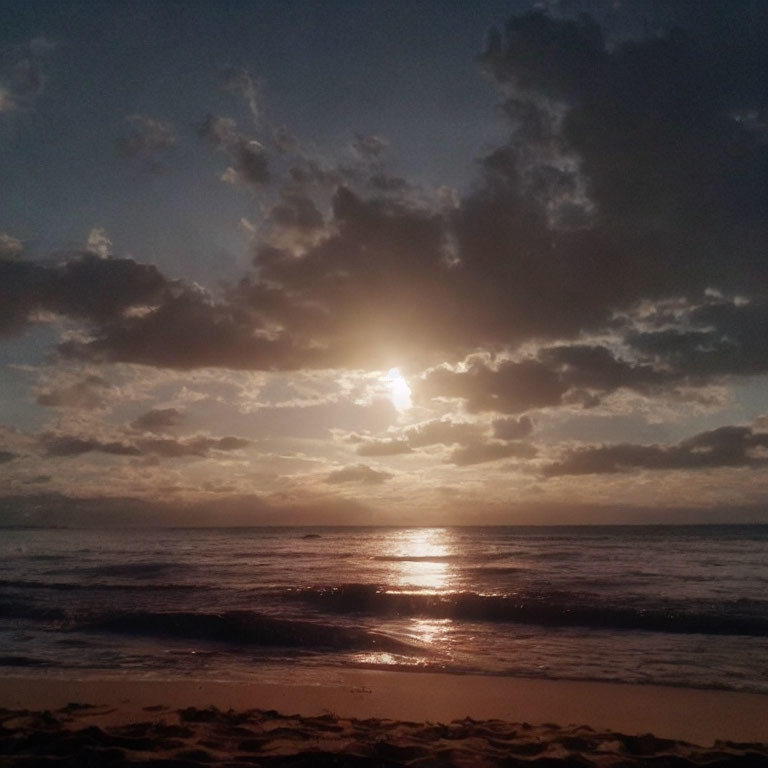 Scattered clouds over sunset ocean view from sandy beach