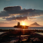 Tranquil sunset seascape with small island and rocky shores at twilight