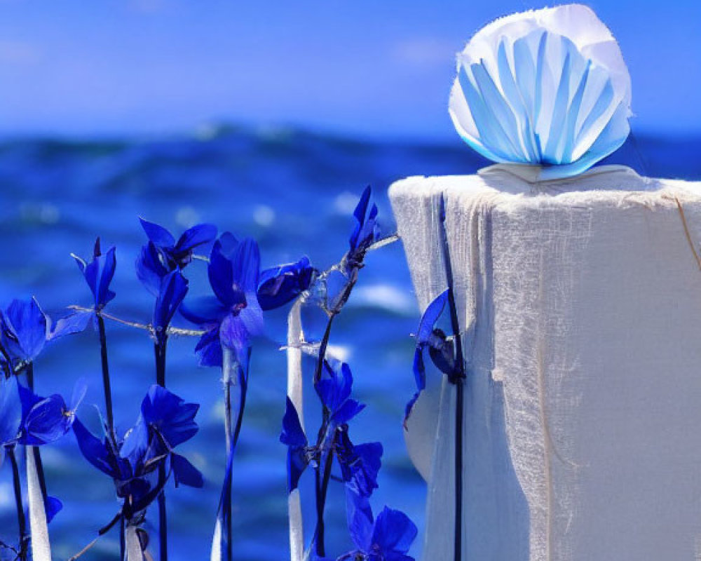 Tranquil beach scene with white cloth, blue decoration, and vibrant flowers