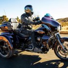 Futuristic robot in sleek armor on heavy-duty motorcycle in cityscape at sunrise or sunset