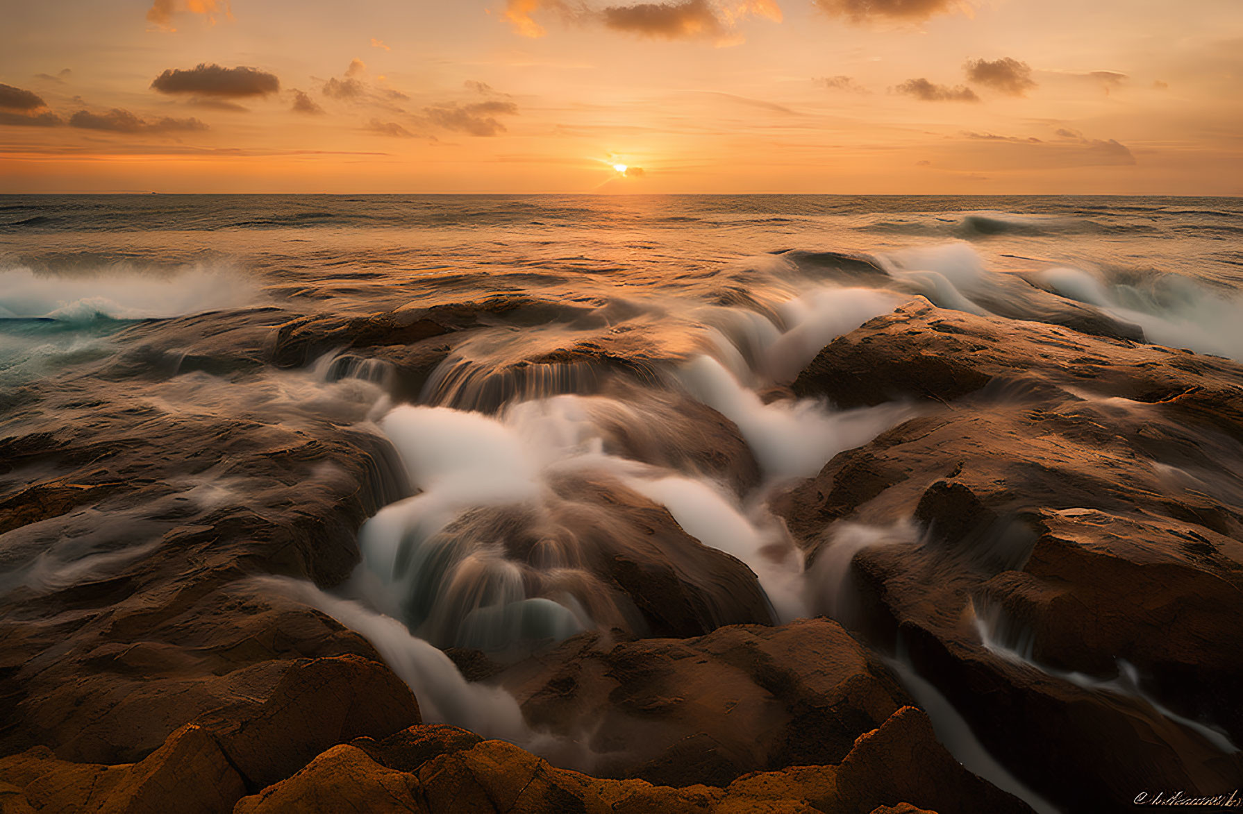 Rocky Shoreline at Sunset with Waves and Clouds