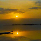 Tranquil sunset seascape with lone boat, golden sky, and birds