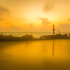 Tranquil sunset seascape with lighthouse, boats, and birds