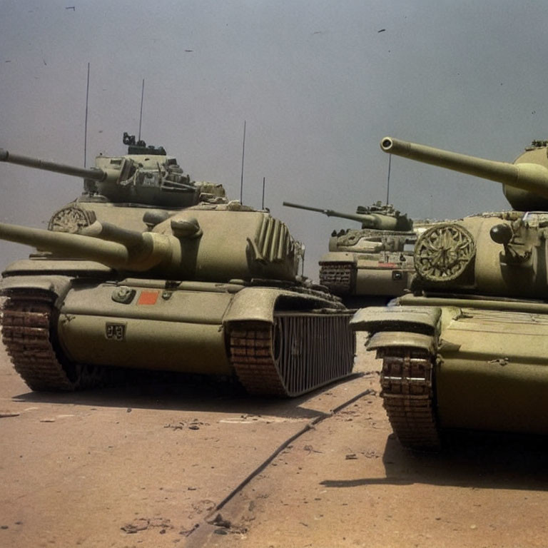 Lineup of Military Tanks on Sandy Terrain with Raised Gun Barrels