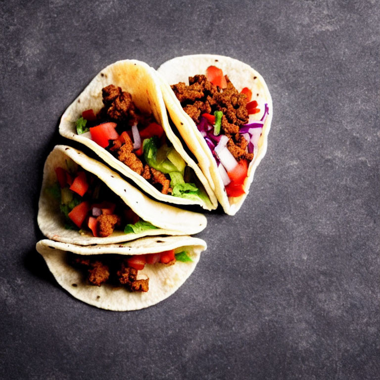 Three Ground Meat Tacos with Lettuce, Tomatoes, and Red Onions