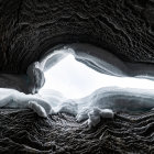 Dark Cave with Alien-like Textures and Solitary Figure gazing at Bright Exit