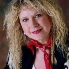 Portrait of smiling woman with blonde hair, blue eyes, and floral blue jacket