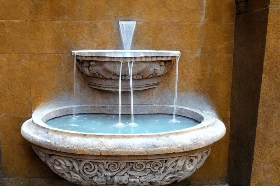 Stone fountain with water flowing into basin against tiled wall