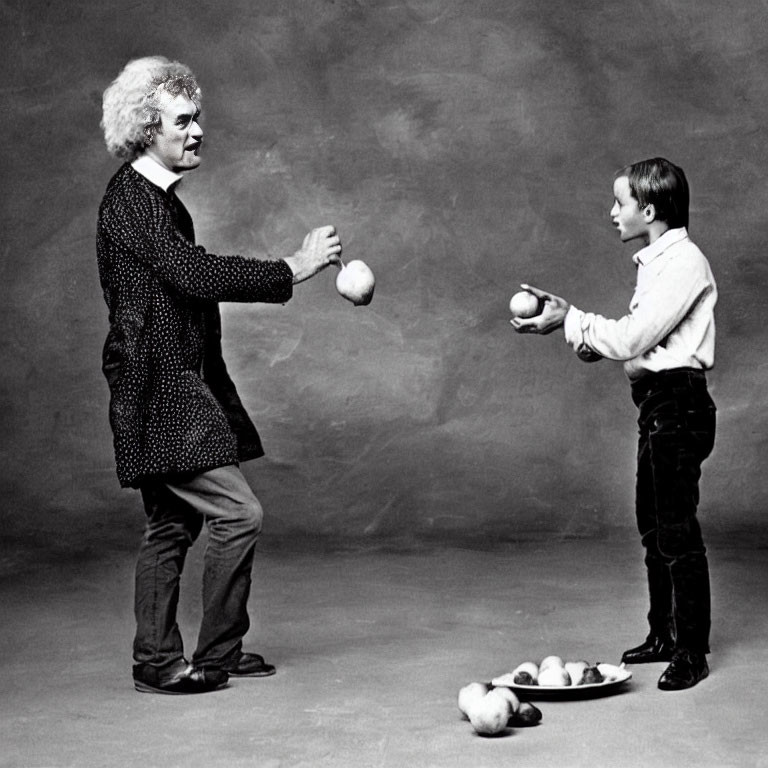 Adult and child juggling balls in front of each other