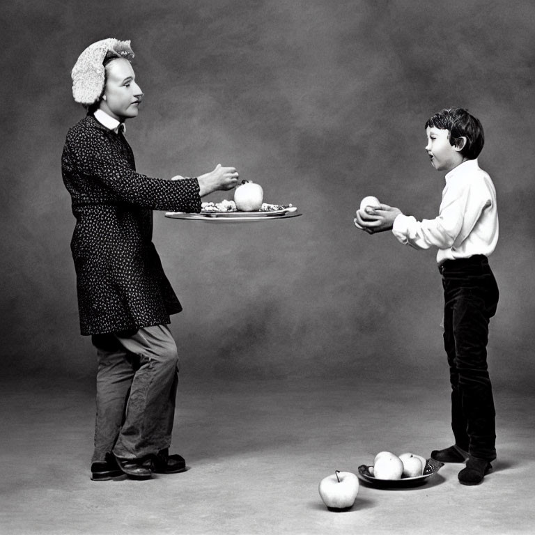 Adult in textured coat offers fruit to child in fluffy hat.