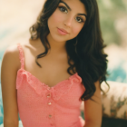 Illustrated woman with dark hair in floral pink dress holding flowers on bokeh background