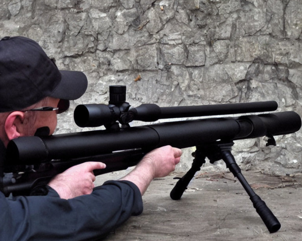 Person in Black Cap Aiming Sniper Rifle at Stone Wall