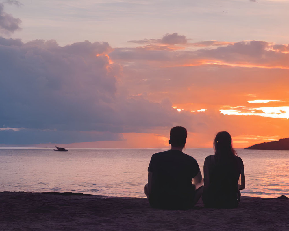 Beach sunset scene with two people and boat silhouette