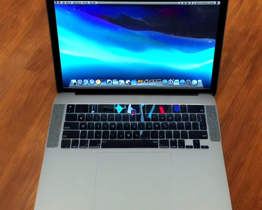 Laptop on Wooden Table with Cosmic Wallpaper and Trackpad