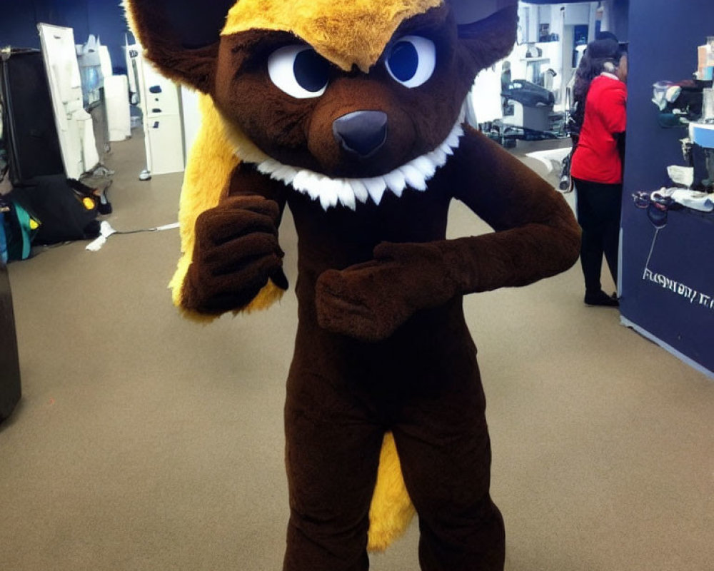 Brown Mascot Costume of Animated Fox with Big Eyes and Sharp Teeth Standing Indoors