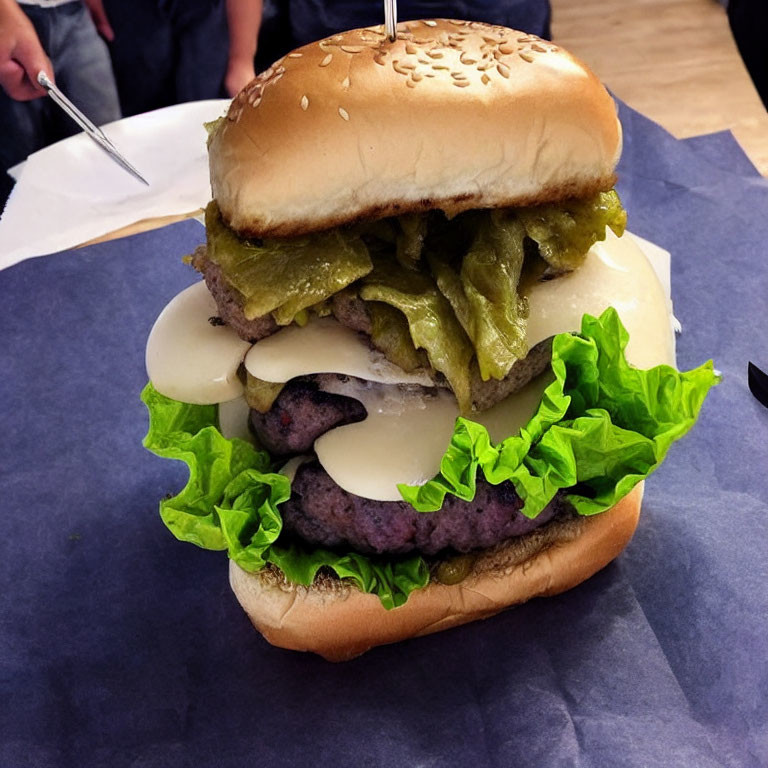 Giant multi-patty cheeseburger with lettuce, pickles, sesame bun