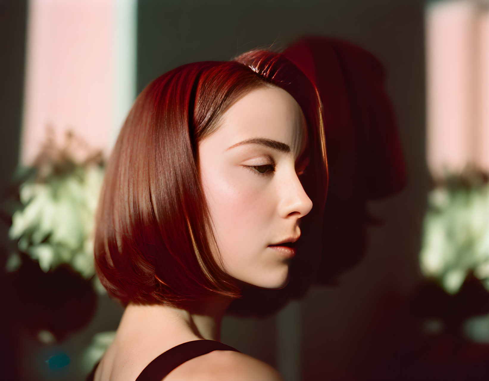 Sleek Asymmetrical Red Bob Haircut on Woman with Thoughtful Gaze