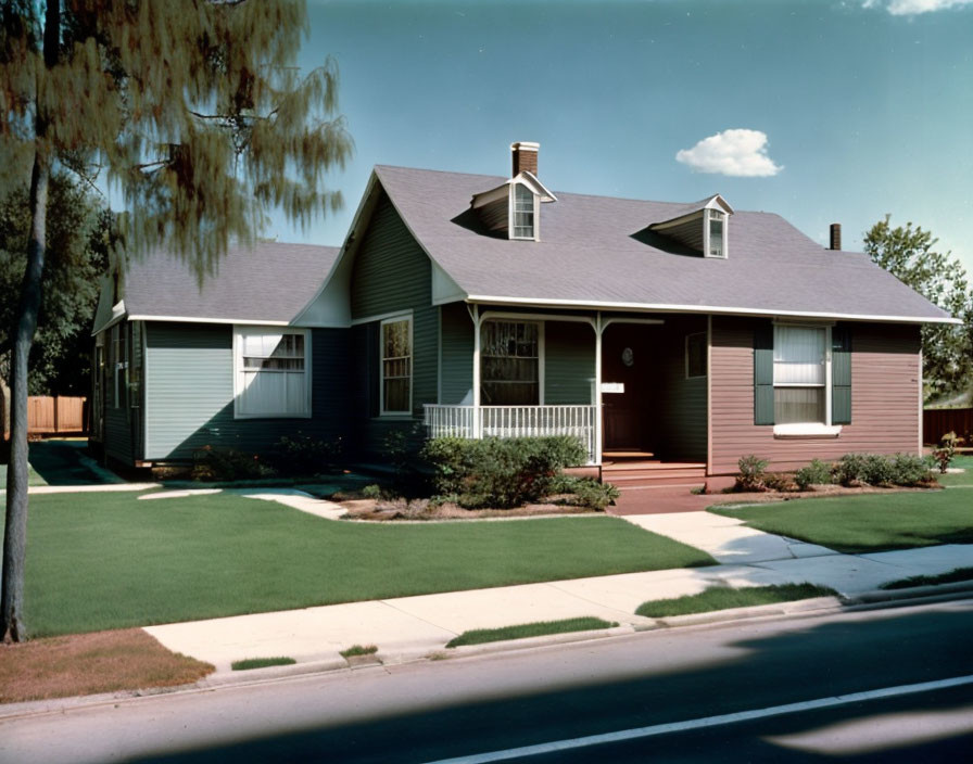 Suburban house with sloped roof, red and blue siding, front porch, and manicured lawn