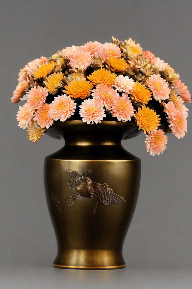 Bronze vase with embossed bird design and pink-orange chrysanthemums