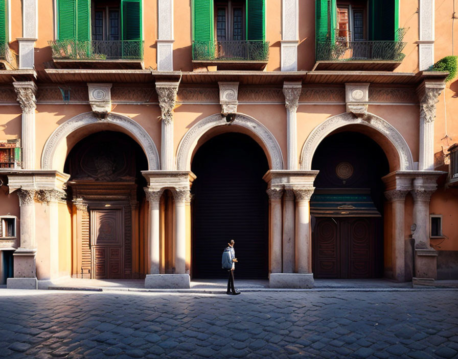 Person standing between two arched doorways on cobblestone street in sunlight.