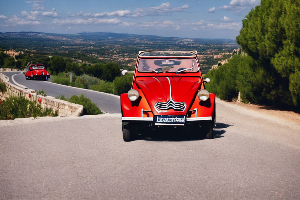 Vintage Red Car Drives on Scenic Road Amid Hilly Landscape