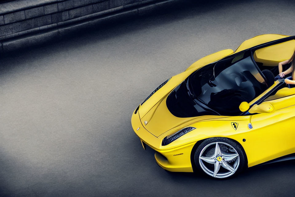 Yellow Sports Car with Aerodynamic Design and Iconic Emblem on Grey Asphalt