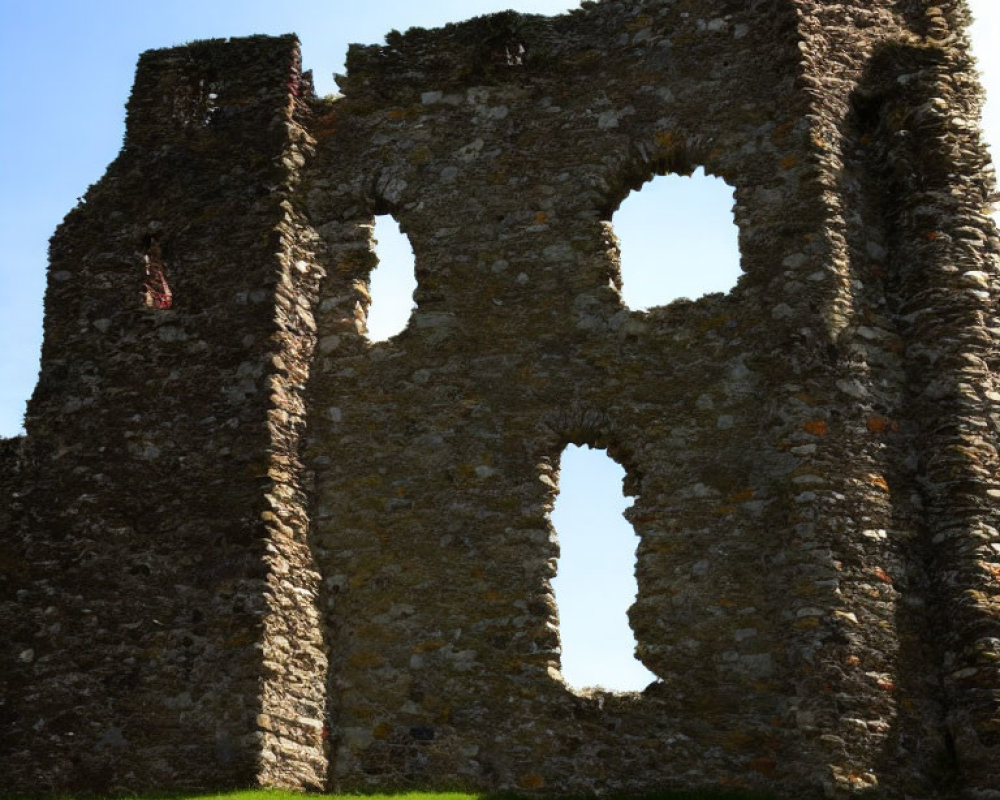 Ancient stone building ruins with large arched windows on clear blue sky