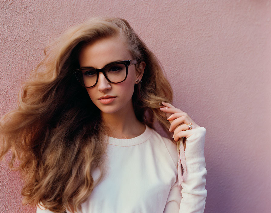 Blonde woman with glasses in white shirt on pink background