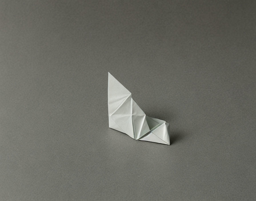 Origami white paper boat on grey background