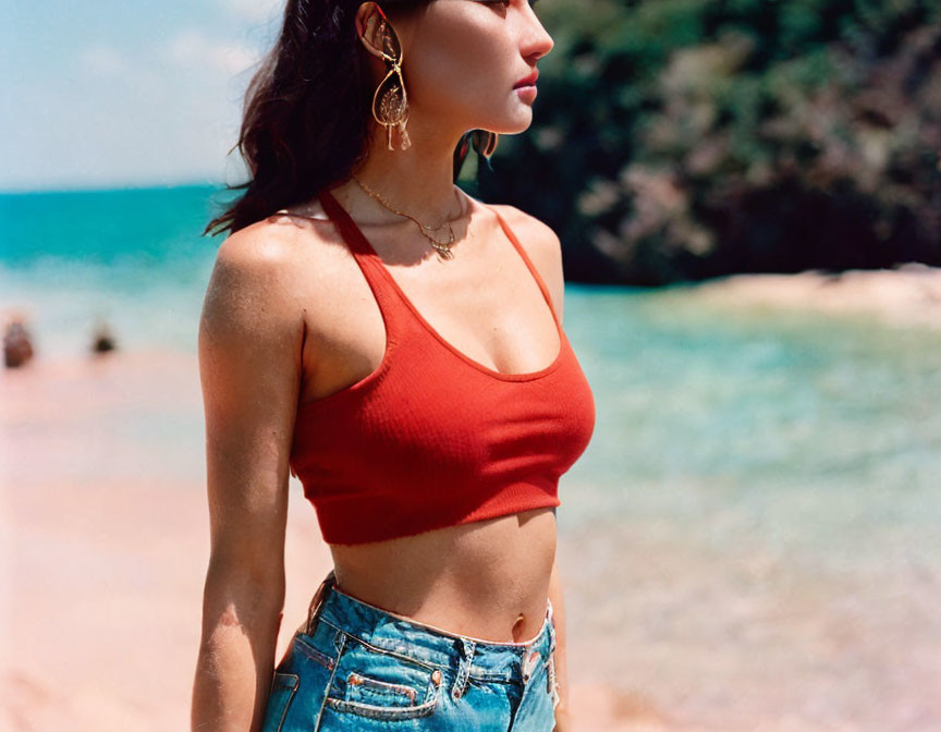 Woman in red top and blue jeans on beach with sea and sky view