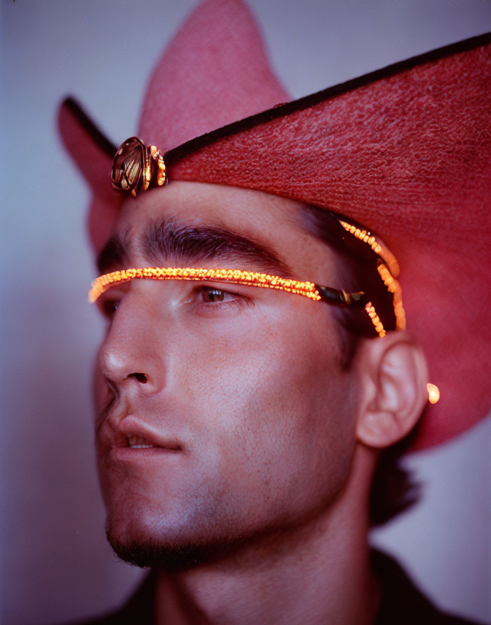 Person in Red Cowboy Hat and Orange Illuminated Eyewear, Serious Expression