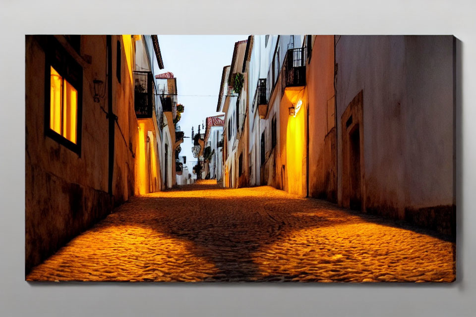 Traditional cobblestone street at twilight with warm streetlights and white buildings.