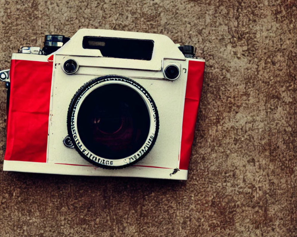 Vintage Red and White Camera with Large Lens on Textured Beige Wall